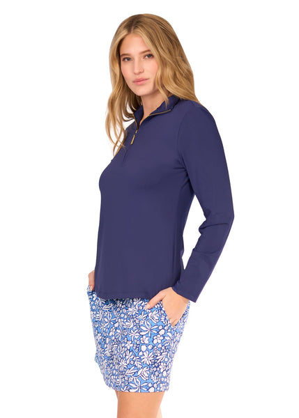 The side of a blonde woman wearing the sun protective Navy 1/4 Zip Sport Top and navy floral patterned Seaside 17" Skort from Cabana Life on a white background.