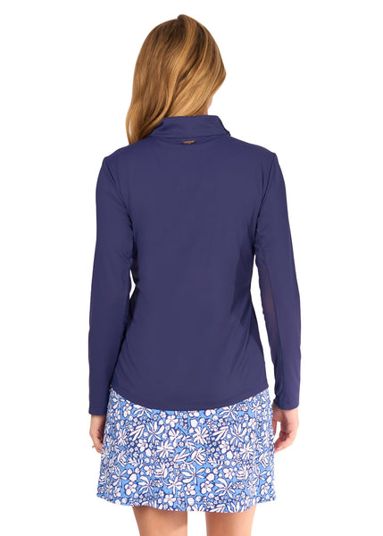 The back of a blonde woman wearing the sun protective Navy 1/4 Zip Sport Top and navy floral patterned Seaside 17" Skort from Cabana Life on a white background.